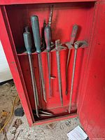 Overall view of chisels and pry bars inside red cabinet