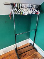 Full view of garment rack with hangers on top bar, showing lower shelf and base supports.