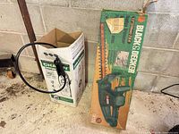 Cardboard boxes for Black & Decker hedge trimmer and Chapin sprayer visible