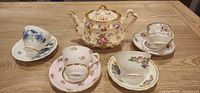 Group image showing teapot and four mismatched cup-and-saucer sets