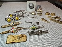 Overview of cufflinks, tie clips, chain, money clip on fabric surface