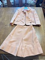 Full view of peach jacket and skirt laid flat on table