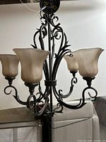 Full view of five-light chandelier showing all glass shades and metal frame