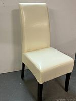 Overall front-left view of cream faux leather dining chair