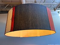 Side view of cylindrical fabric lampshade showing grey, red, cream panels and stitching
