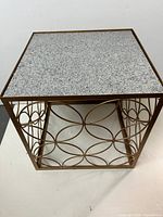 Full view of square table showing stone top and gold circular frame