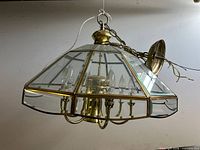 Full view of octagonal brass and beveled glass chandelier hanging, showing overall design and six lights