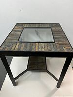 Full view of square end table showing tile top, glass insert, metal frame, lower shelf
