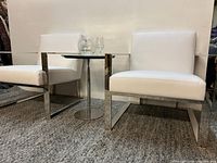 Two white leatherette chairs beside small table