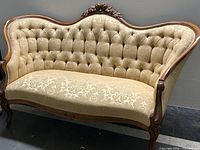 Full front view of sofa showing carved crest rail, tufted back, seat and legs