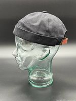 Left side profile of black hat on glass head form