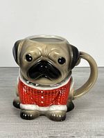 Front view of sculpted pug mug showing sweater detail and facial features