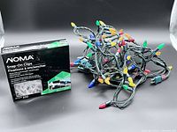 Box of NOMA Snap-On Clips next to bundled multicolour string lights