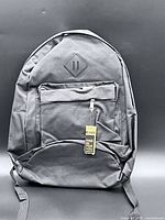 Front view of black backpack showing front pocket, diamond patch, hangtag