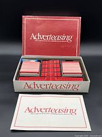 Closed and open box showing game components including card decks, score sheets and timer