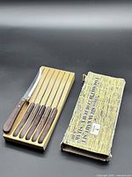 Six Henckels serrated steak knives in wood block with worn cardboard sleeve