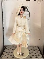 Full view of doll on stand with outfit and accessories