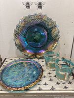 Both iridescent chargers and two decorated tumblers