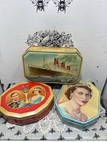 All three tins grouped: ship tin upright, red octagonal royal tin, turquoise royal tin