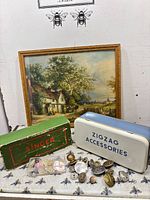 Lot overview showing framed print, Singer box, Zigzag case, buttons