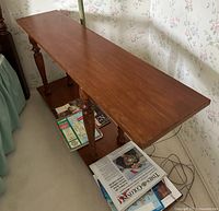 First console table showing top surface, turned legs, lower shelf with magazines