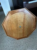 Full view of octagonal wooden Crokinole board showing scoring rings and centre hole.