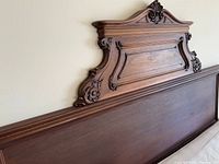 Angled view of entire carved headboard showing French style crest and lower board