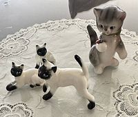 Front view of all four cat figurines on lace mat