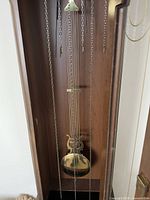 Interior view showing brass pendulum disc, chains, movement components