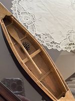 Top view of wooden canoe interior showing paddle and cross-braces