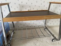 Overall view of cart showing wood top, chrome legs, slat shelf, casters