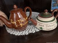 Two teapots side by side on lace doily
