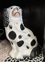 Left-facing spaniel figurine showing spots, chain collar, glaze