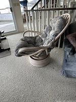 Full view of rattan swivel lounge chair showing base, arms and cushion