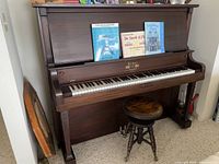Full view of upright piano with stool in front