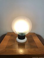 Lamp illuminated from the front showing frosted glass disc and base