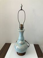 Full view of porcelain table lamp with harp and finial