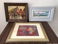 Three framed artworks on table