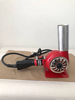 Full view of red Master Appliance heat gun on stand showing nozzle, body and cord