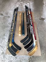 Overall lot—five hockey sticks and two baseball bats laid out