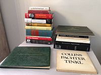 Two stacks of assorted vintage books on table