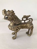 Left-side view of brass Foo Dog showing overall form and tail detail