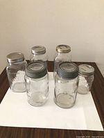 Front view of six assorted mason jars showing varying sizes and lids