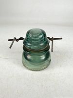 Front view of aqua glass insulator with attached iron tie wire