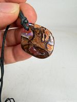 Front view of polished boulder opal pendant on cord