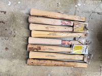 Stack of eight hickory hammer handles showing overall quantity and condition mix