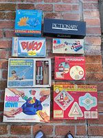 Top-down view of eight vintage board game and toy boxes on brick surface