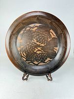 Full view of carved pottery platter on stand showing overall design
