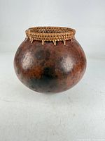 Front view of spherical earthenware vase with wicker rim