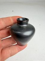 Front view of small dark charcoal glazed vase showing overall shape and neck